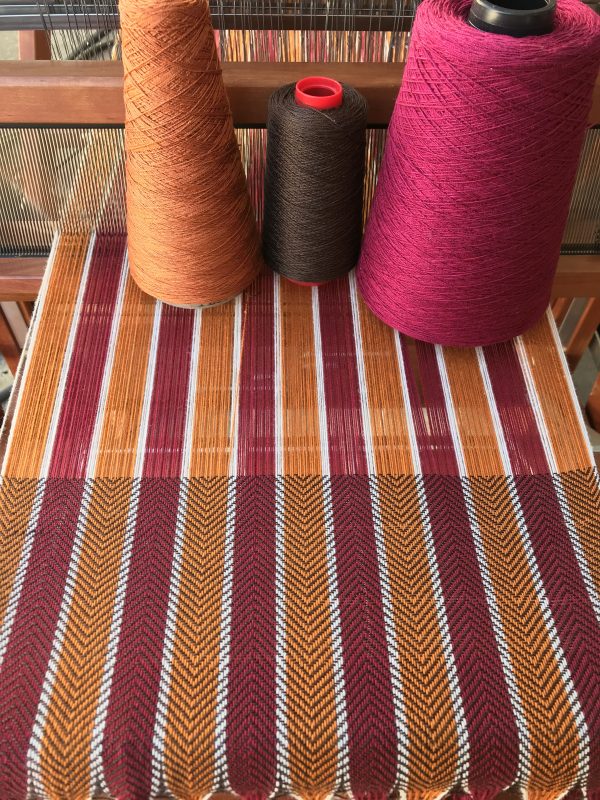 gold, burgundy, and brown yarns on fabric