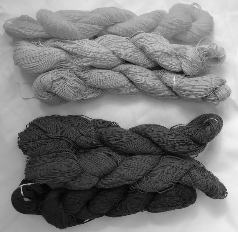 The same skeins in black and white. The top three skeins are nearly the same shade of light gray. THe bottom three skeins are dark to very dark gray.